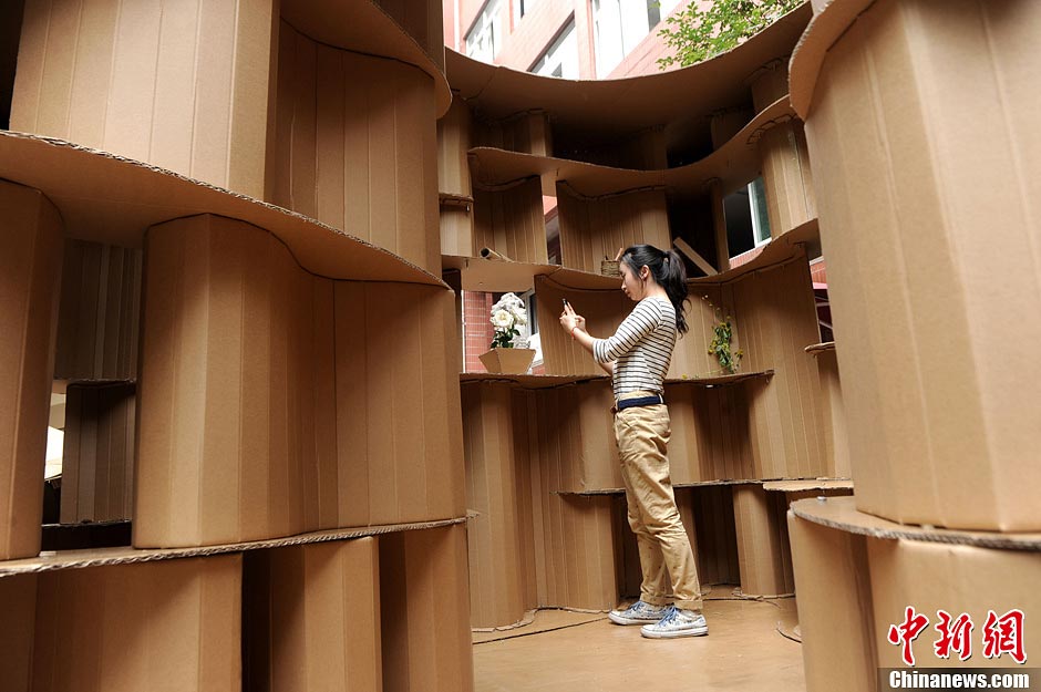 A student takes photos inside a house made of paper boxes at Chongqing University in Southwest China's Chongqing Municipality, May 20, 2013. (CNS/Chen Chao)