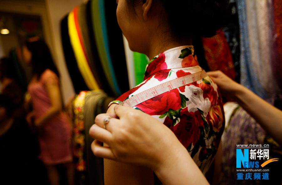 Shi Yuhong takes client's measurements in Chongqing on March 29, 2013. Each cheongsam was handmade according to client's measurements. (Photo/Xinhua)