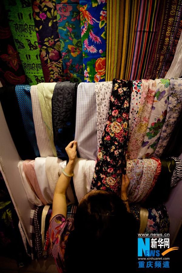 Liang Li chooses the fabric for making cheongsam in a shop in Yuzhong district in Chongqing on March 29, 2013. (Photo/Xinhua)