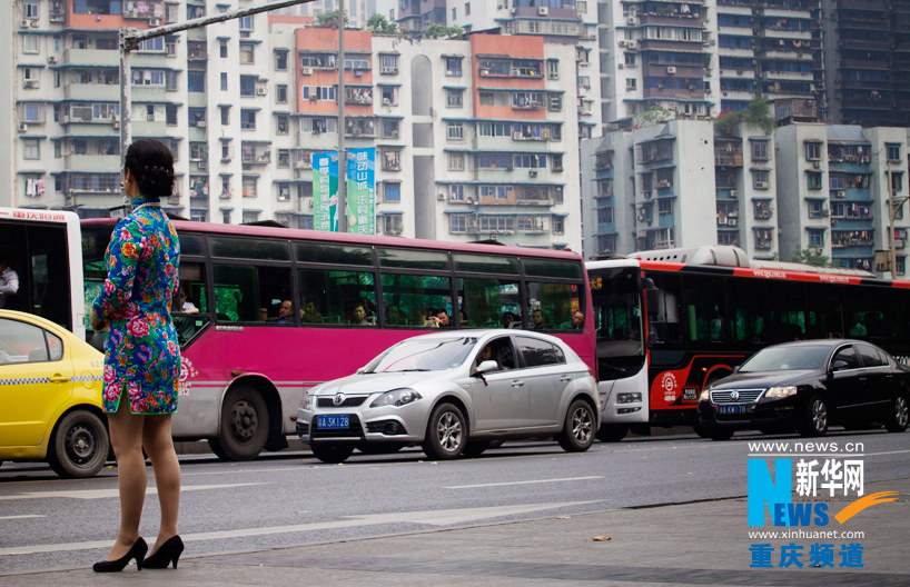 Lili, in cheongsam, waits for a taxi on the road side. Cheongsam is her daily dress. (Photo/Xinhua)  