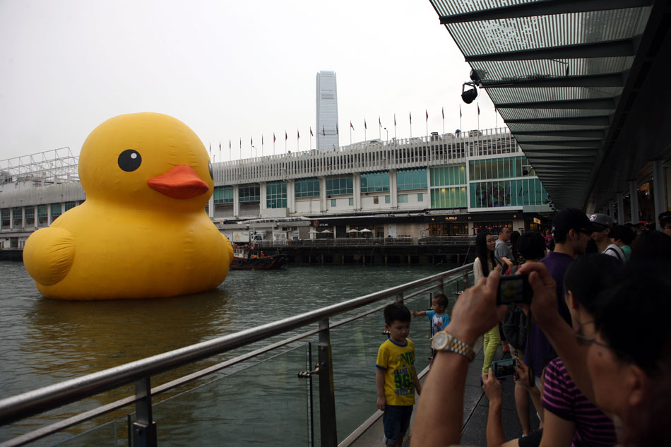 Visitors take photo with the rubber duck in Hong Kong on May 22. 2013. The giant inflatable rubber duck returns to Victoria Harbor, Hong Kong, May 21, 2013. It was abruptly deflated for maintenance for almost a week. The 16.5-meter-tall duck, conceived by Dutch artist Florentijn Hofman, sailed into the harbor on May 2 to cheering crowds. (Xinhua Photo/ Wang Yuqing)