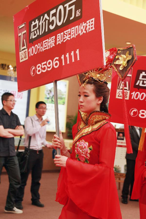 A girl wearing ancient Chinese costumes publicizes for an exhibitor during the 55th Housing Fair held in Nantong City, east China's Jiangsu Province, May 24, 2013. The housing fair, featuring different kinds of publicizing methods, opened in the Nantong on Friday. (Xinhua/Cui Genyuan)