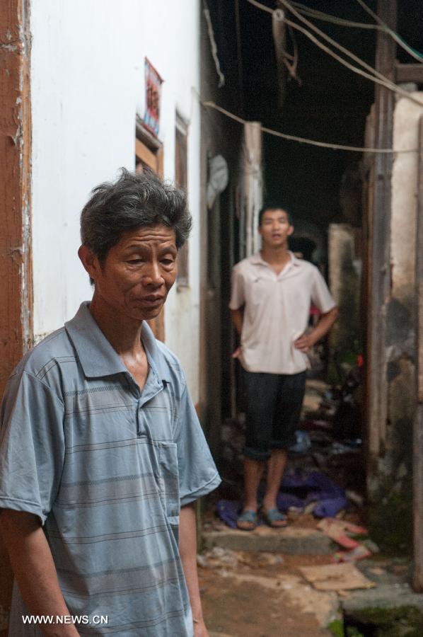 Zhong Yongxiang (front), 59, and his 27-year-old son Zhong Yun stand in their flooded house in Legan Village of Jiaoling County, Meizhou City, South China's Guangdong Province, May 23, 2013. Zhong has two sons, one of whom attending school outside their hometown and another suffering from cerebral palsy, which makes life more difficult for the family after the rainstorm hitting Guangdong Province on May 18. With the youth attending school or working outside their hometowns, the left-behind family members are becoming even more vulnerable after natural disasters. (Xinhua/Mao Siqian)  