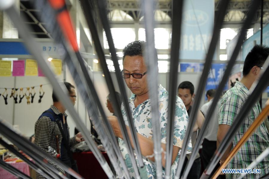 A fishing fan selects fishing rod at the 3rd Yinchuan fishing gear expo in Yinchuan, capital of northwest China's Ningxia Hui Autonomous Region, May 25, 2013. (Xinhua/Li Ran)