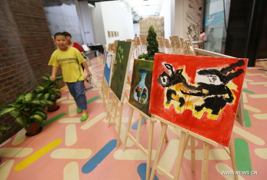 Visitors view paintings at a painting exhibition at the 798 art area in Beijing, capital of China, May 25, 2013. A two-day exhibition kicked off on Saturday, displaying paintings created by over 20 mentally retarded children from Chaoyang Anhua School. (Xinhua) 