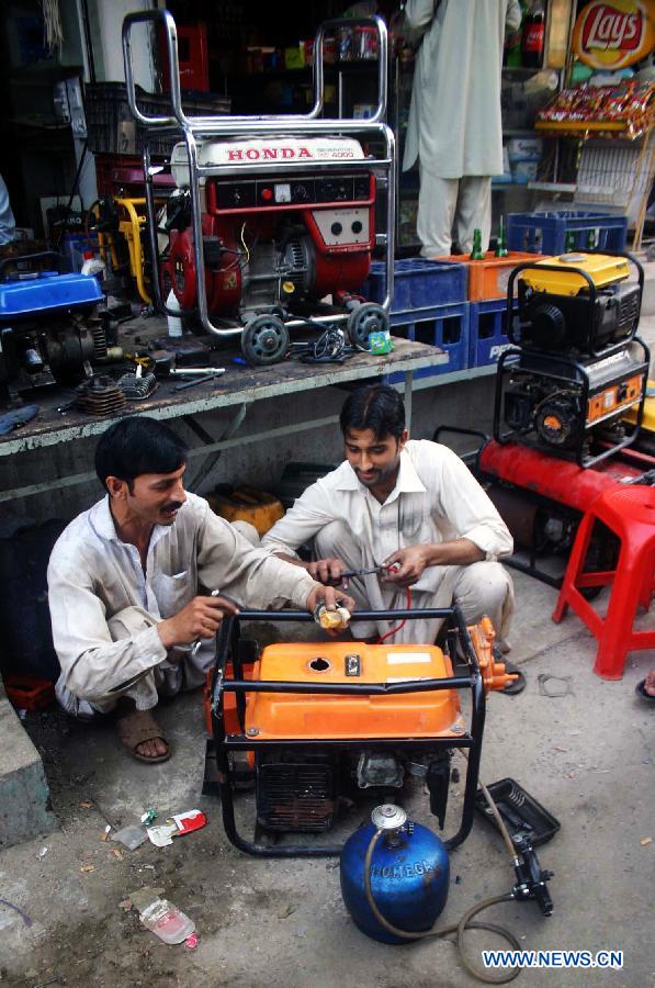 Workers repair electric generators at a workshop in Peshawar, northwest Pakistan, May 26, 2013. Power shortfall across the country has reached over 5,500 megawatts. (Xinhua/Ahmad Sidique)