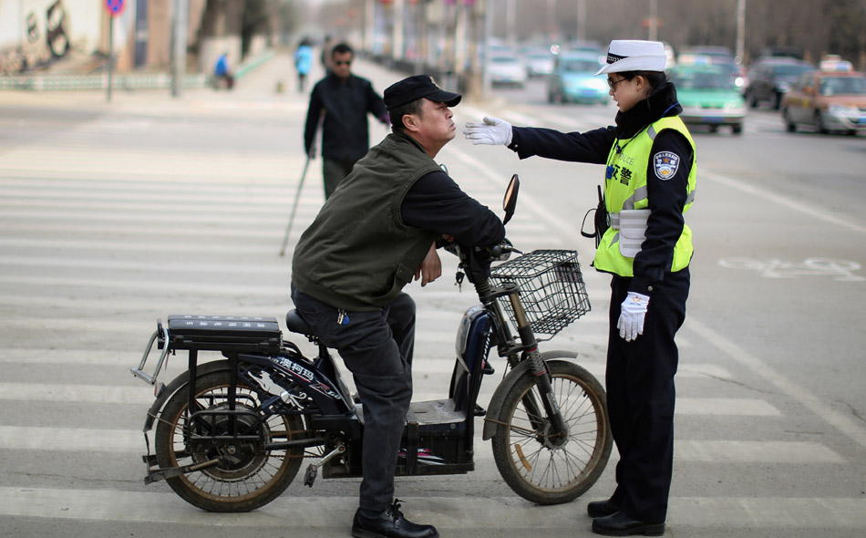 A police officer urges a citizen to go back to stop line in Shenyang, capital city of Liaoning province. The woman police officer is one of the 77 image ambassadors of the city. (Xinhua Photo/ Yao Jianfeng)