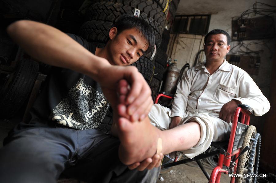 Lan Chuan (L) massages a foot of his father Lan Zhongguo at Fozi Village in Shanglin County of Nanning City, capital of southwest China's Guangxi Zhuang Autonomous Region, May 26, 2013. Lan, a 15-year-old middle school student, lives with his paralyzed father on fixing farming machines. Without the care of mother who left the family when he was three years old, Lan takes care of his father and supports his family by aiding him with the fixing work. His story has moved many people in the region, which also brought him the title of "juvenile of virtues " of Nanjing in 2012. (Xinhua/Lu Boan)