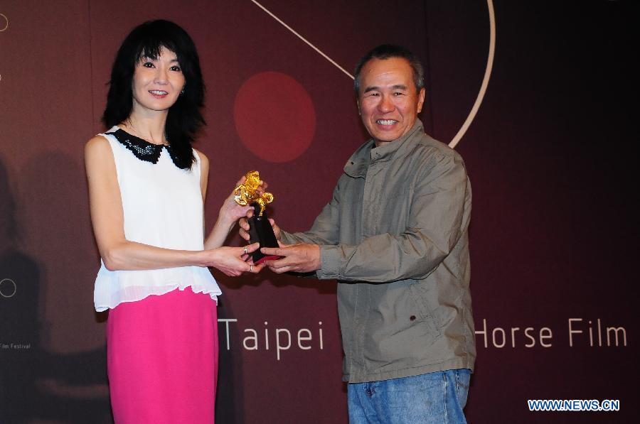 Hou Hsiao-hsien (R), chairman of Golden Horse Film Festival, presents a Festival Ambassador trophy to actress Maggie Cheung during a press conference marking the beginning of the 50th anniversary celebration of the Festival in Taipei, southeast China's Taiwan, May 27, 2013. Maggie Cheung, the actress who won the most Golden Horse Awards so far, is appointed as the 2013 Golden Horse Film Festival Ambassador on Monday. (Xinhua)  