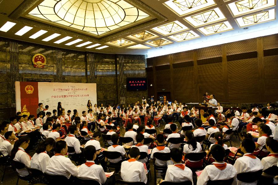 Students gather to listen to an introduction by Sun Jungong, spokesman of the Supreme People's Court, at the first courtroom of the Supreme People's Court in Beijing, capital of China, May 30, 2013. More than 120 students and teachers from Banchang Elementary School and No. 166 Middle School visited the Supreme People's Court on its open day on May 30. (Xinhua/Wang Quanchao)
