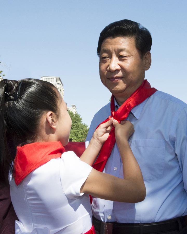 A girl helps Chinese President Xi Jinping wear a red scarf during a children's activity in Beijing, capital of China, May 29, 2013. (Xinhua/Li Xueren) 