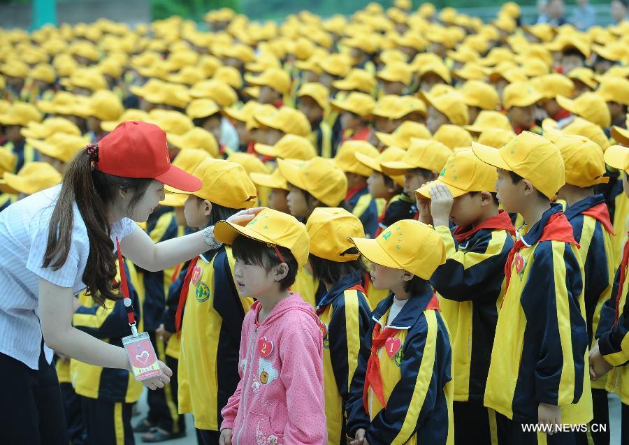 A volunteer talks with a pupil at Xinguang Yucai Elementary School in the Wanzhou District of Chongqing, southwest China, May 31, 2013. Various activities are held across China to celebrate the coming International Children's Day. (Xinhua/Zhou Hengyi) 