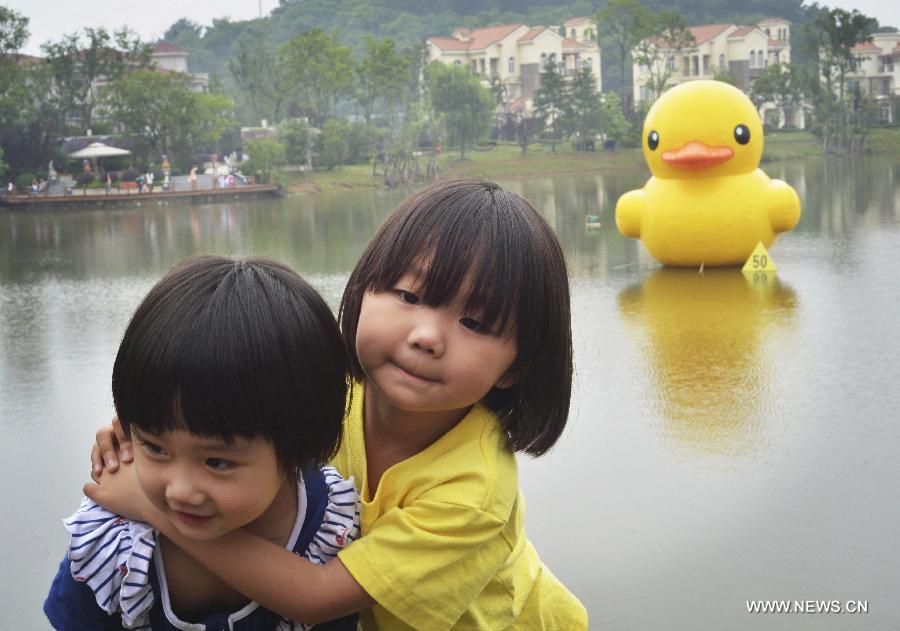 Children play near a mini rubber duck floating on a lake in the Hannan District of Wuhan, capital of central China's Hubei Province, June 1, 2013. The duck, made by a property company, is a mini copy of the huge rubber duck which appeared in Hong Kong, south China, on May 2. (Xinhua)