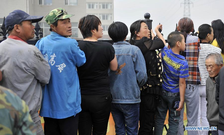 Family members of missing workers and local residents wait for information at the accident site after a fire occurred in a slaughterhouse owned by the Jilin Baoyuanfeng Poultry Company in Mishazi Township of Dehui City, northeast China's Jilin Province, June 3, 2013. Death toll from the poultry processing plant fire on Monday morning has risen to 119. Over 300 workers were in the plant when the accident happened. (Xinhua/Wang Haofei)