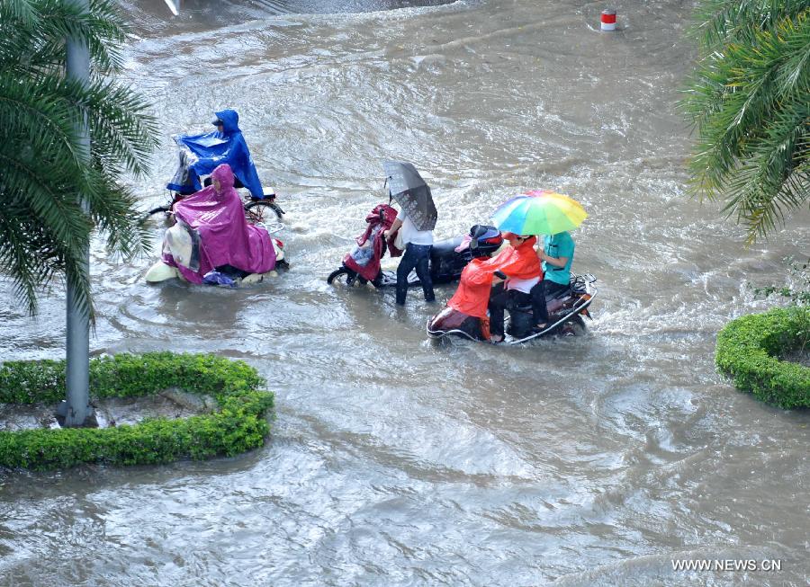 People ride in floods in Nanning City, south China's Guangxi Zhuang Autonomous Region, June 4, 2013. A heavy rainfall hit Nanning on Tuesday, and local meteorological authorities issued an orange alert for rainstorms. China has a four-color warning system for strong rain, with red being the most serious, followed by orange, yellow and blue. (Xinhua/Zhou Hu)