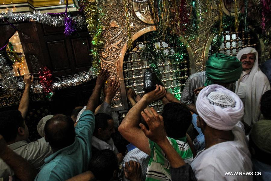 Egyptian Sufi Muslims touch the tomb of Sayeda Zainab for blessings inside Al-Maqam Al-Zainaby mosque during a celebration of the birth anniversary of Sayeda Zainab, who is the granddaughter of Prophet Muhammad, in Cairo, Egypt, June 5, 2013. (Xinhua/Amru Salahuddien)