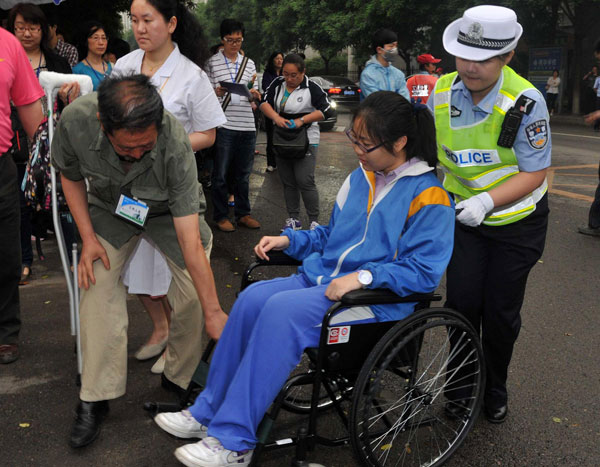 A traffic policewoman and a teacher help a student into a test site, June 7, 2013. [Photo/Xinhua]