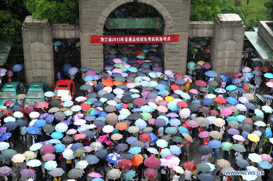 Parents holding umbrellas wait in rain as their children taking the national college entrance exam at the Hangzhou High School in Hangzhou, capital of east China's Zhejiang Province, June 7, 2013. Some 9.12 million applicants are expected to sit this year's college entrance exam on June 7 and 8. (Xinhua/Ju Huanzong)