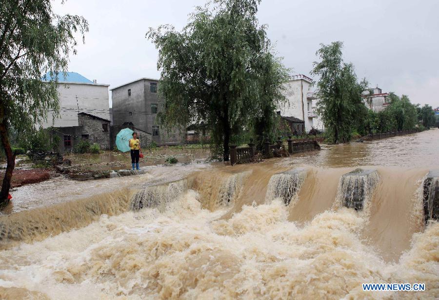 A woman stands in floods triggered by torrential rains in Xubu Town, Duchang County, east China's Jiangxi Province, June 7, 2013. Heavy rain began to affect Duchang on Thursday and continued into Friday morning, with the average precipitations in excess of 150 mm, and made some houses, roads and fields flooded. (Xinhua/Fu Jianbin)
