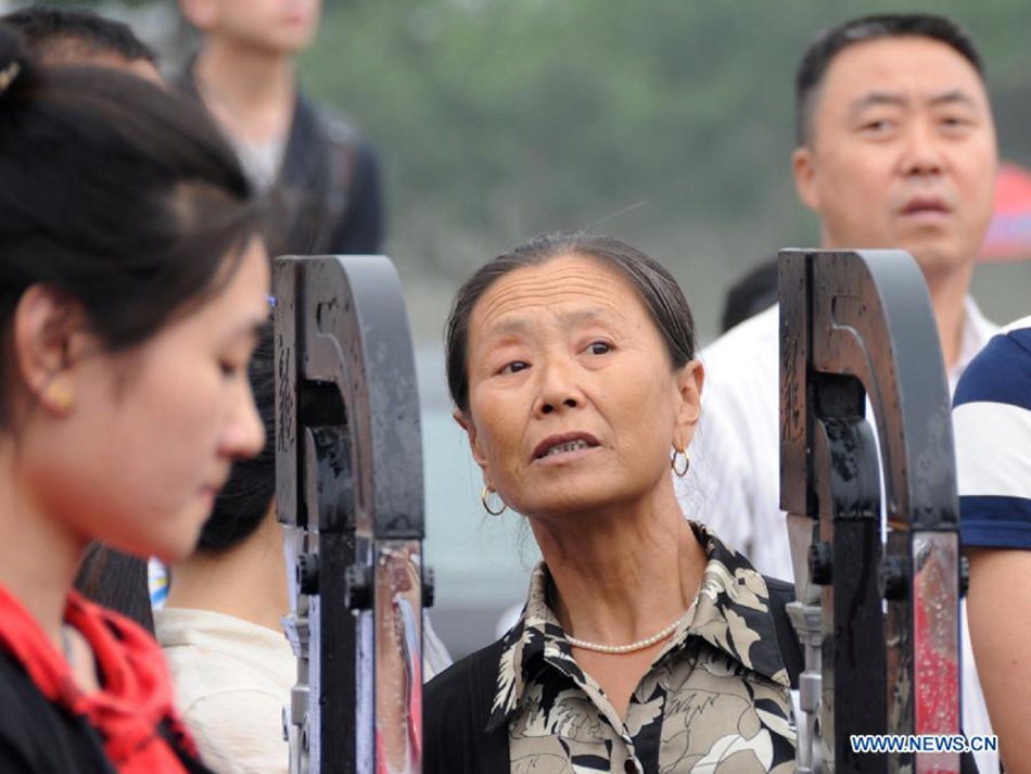 A mother waits for her kid taking the national college entrance exam in Gu'an, north China's Hebei Province, June 7, 2013. Some 9.12 million applicants are expected to sit this year's college entrance exam.