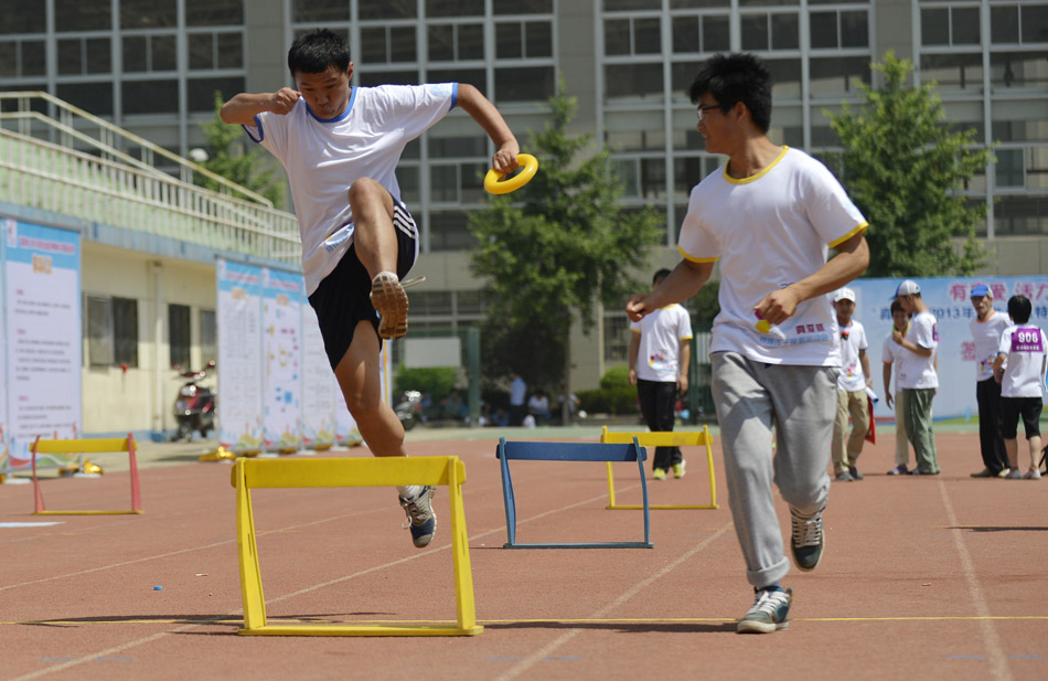 A disabled child accompanied by a volunteer is in a hurdle race in Xi'an, Shaanxi province on June 1, 2013. (Xinhua/Liu Xiao)
