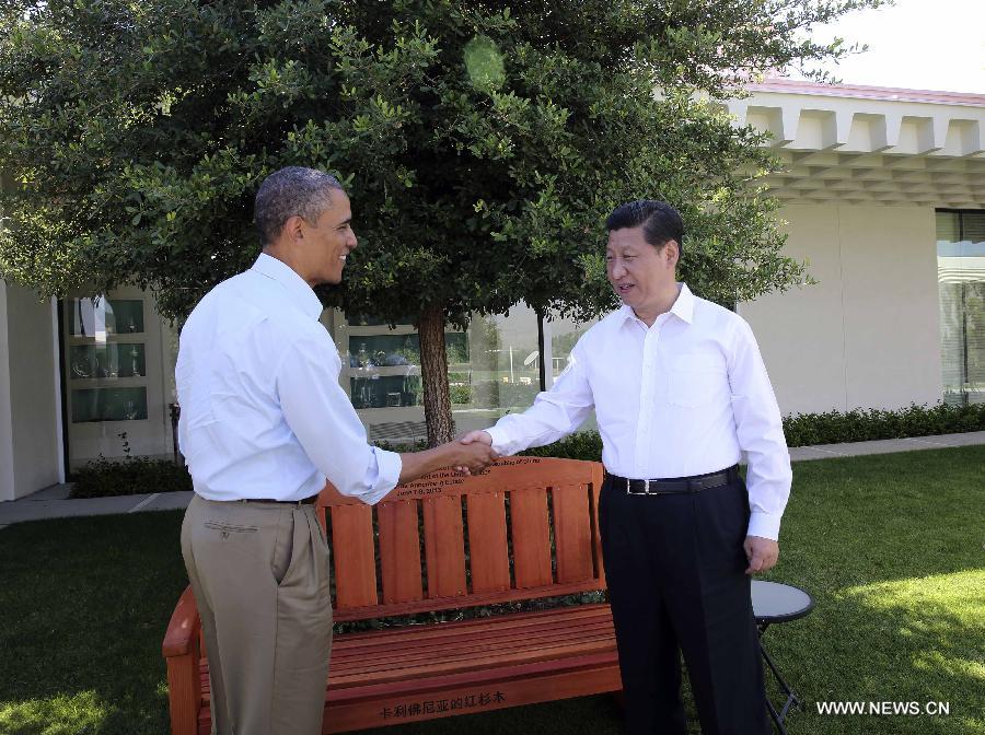 U.S. President Barack Obama (L) presents Chinese President Xi Jinping with a bench made of California redwood while they take a joint walk before heading into their second meeting, at the Annenberg Retreat, California, the United States, June 8, 2013. Chinese President Xi Jinping and U.S. President Barack Obama held the second meeting here on Saturday to exchange views on economic ties. (Xinhua/Lan Hongguang) 