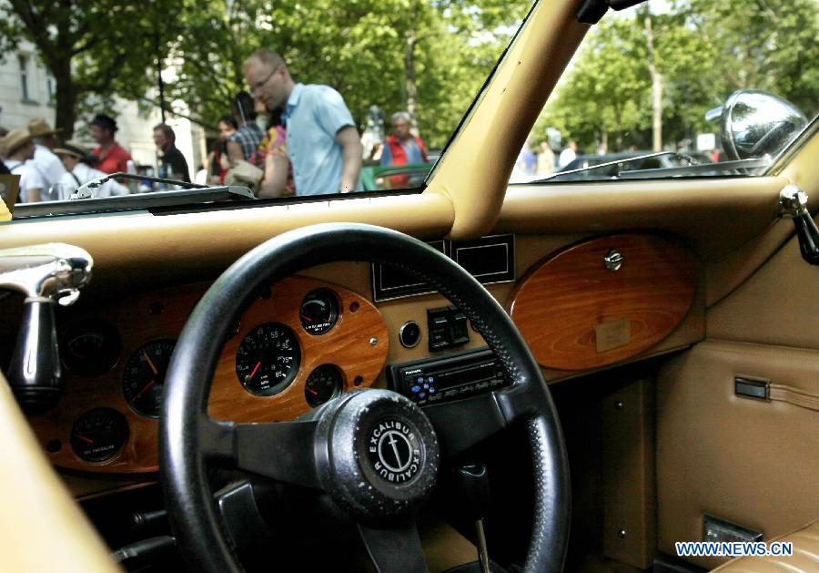 A visitor appreciates a classic old-timer car during a grand exhibition of the classic vintage cars, on the Kurfuerstendamm Avenue, in Berlin, Germany, June 8, 2013. Some 2,000 well-preserved and well-functioning classic vintage cars and limousines at least over 50-year-old are exhibited at the fair, with the motto "when luxury meets classics". (Xinhua/Pan Xu) 