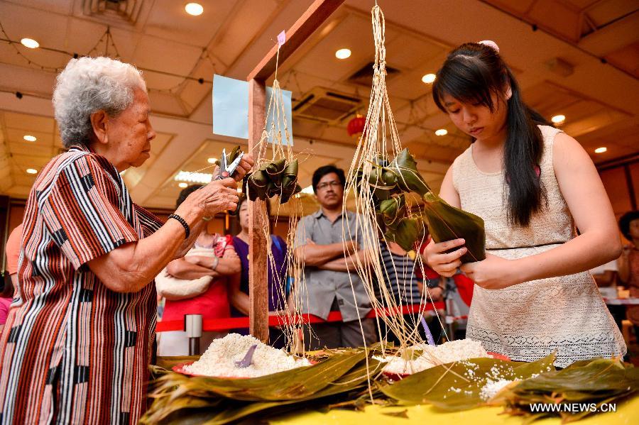 Contestants make Zongzi, a pyramid-shaped dumpling made of glutinous rice wrapped in bamboo or reed leaves, during a contest in celebration of the upcoming Dragon Boat Festival in Kuala Lumpur, Malaysia, June 9, 2013. The contest was held by a local Chinese association to promote the traditional Chinese festival -- Dragon Boat Festival, which falls on the fifth day on the fifth month on the lunar calendar. (Xinhua/Chong Voon Chung)
