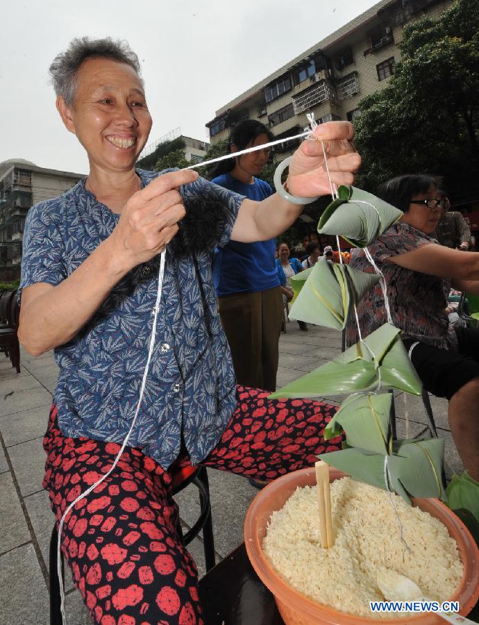 A contestant makes Zongzi, a pyramid-shaped dumpling made of glutinous rice wrapped in bamboo or reed leaves, during a contest in celebration of the upcoming Dragon Boat Festival in Changsha, capital of central China's Hunan Province, June 9, 2013. The Dragon Boat Festival falls on the fifth day on the fifth month on the lunar calendar. (Xinhua/Long Hongtao) 