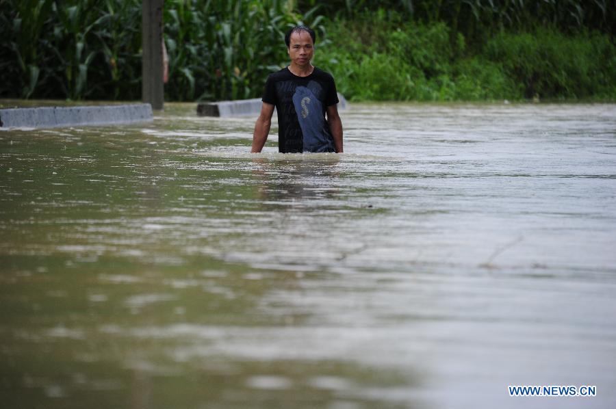 A villager walks in floods in Long'an Town, Luocheng County, south China's Guangxi Zhuang Autonomous Region, June 9, 2013. A new round of torrential rainfall hit Guangxi on Sunday, and local meteorological authorities issued a blue alert for rainstorms. China has a four-color warning system for strong rain, with red being the most serious, followed by orange, yellow and blue. (Xinhua/Wu Yaorong) 