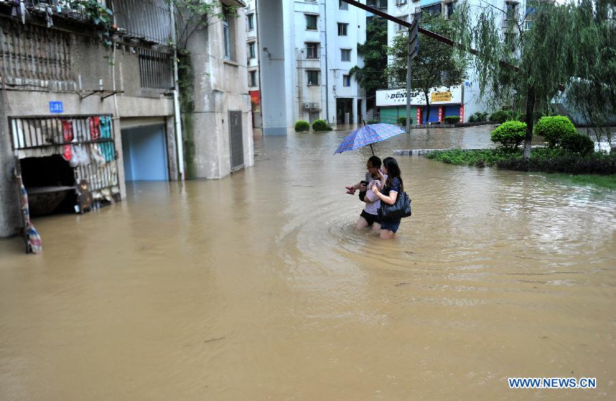 People walk in the flood water on Binjiang West Road in Liuzhou City, south China's Guangxi Zhuang Autonomous Region, June 10, 2013. Liujiang River's flood peak of the year appeared in urban Liuzhou on Monday, with its water level reaching 83.71 meters, 1.21 meters higher than the warning line. (Xinhua/Li Hanchi) 