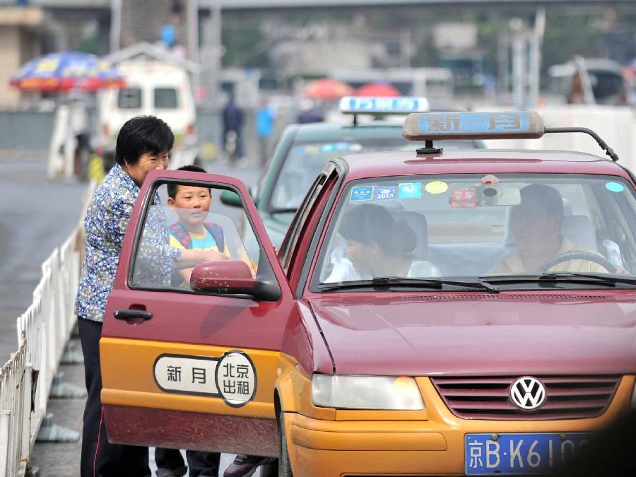 Passengers take a taxi at the Beijing Railway Station in Beijing, capital of China, June 10, 2013. The 3-kilometer base fare for a taxi in Beijing rose by 30 percent from 10 yuan (1.6 U.S. dollars) to 13 yuan as of Monday. According to the new plan, a cab fare will be charged at 2.3 yuan per kilometer after the first 3 kilometers. (Xinhua/Li Wen)