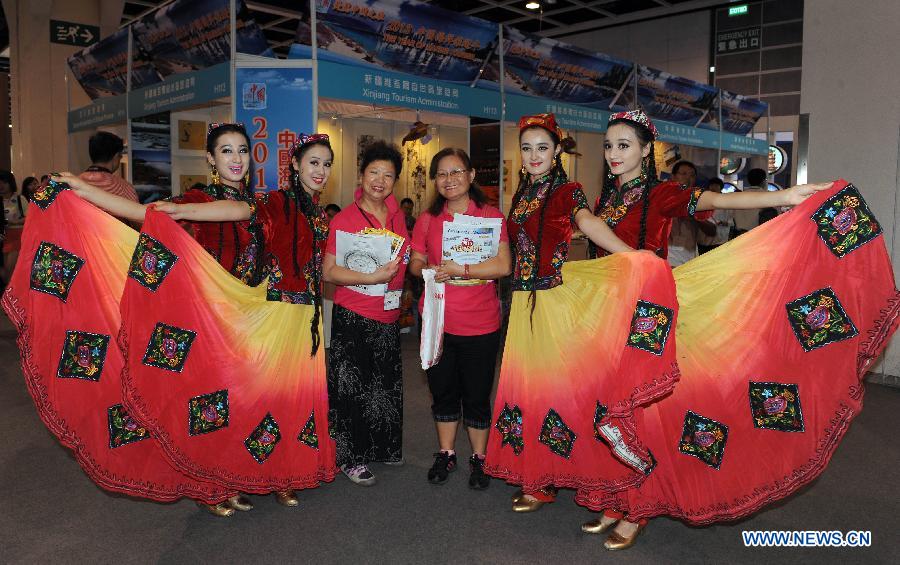 Visitors pose for a group picture with women from northwest China's Xinjiang Uygur Autonomous Region at the 27th Hong Kong International Travel Expo in south China's Hong Kong, June 13, 2013. The four-day expo kicked off here on Thursday at Hong Kong Convention & Exhibition Centre. (Xinhua/Wong Pun Keung)