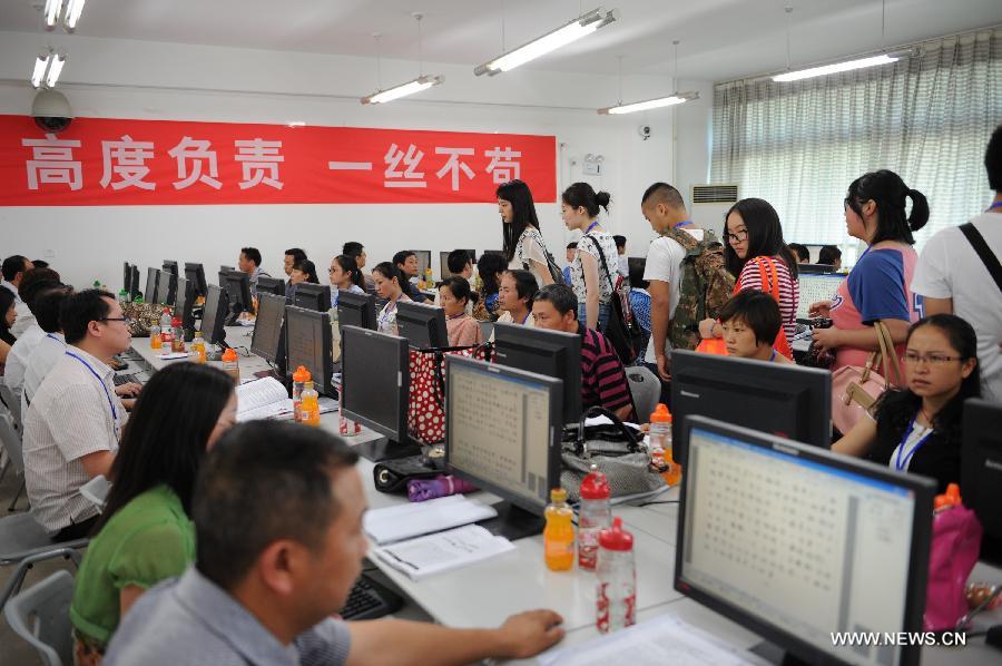 Examinees view the college entrance exam paper marking work at a paper marking room in Guizhou Normal University in Guiyang, capital of southwest China's Guizhou Province, June 14, 2013. The paper marking work in Guizhou opens to several examinees and their parents on Friday. (Xinhua/Liu Xu)