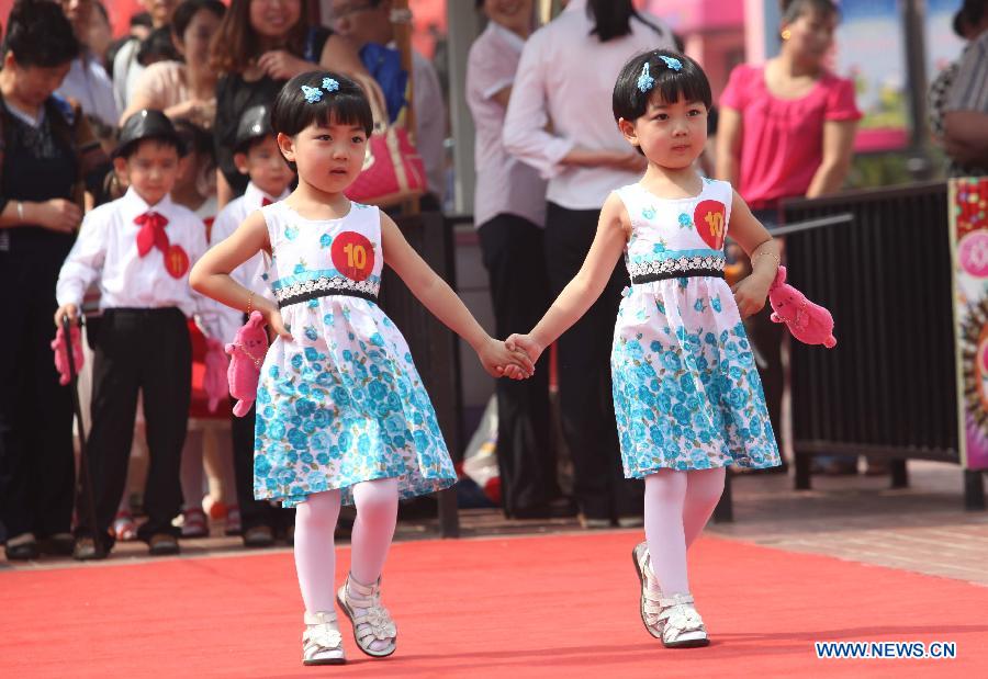 A pair of twins attends the 2013 Shandong (Weifang) First Twin Cultural Festival in Weifang, east China's Shandong Province, June 15, 2013. The festival, in which more than 60 pairs of twins and multiple births from Weifang City showed their talents and exchanged with each others, opened here on Saturday.(Xinhua/Zhang Chi) 