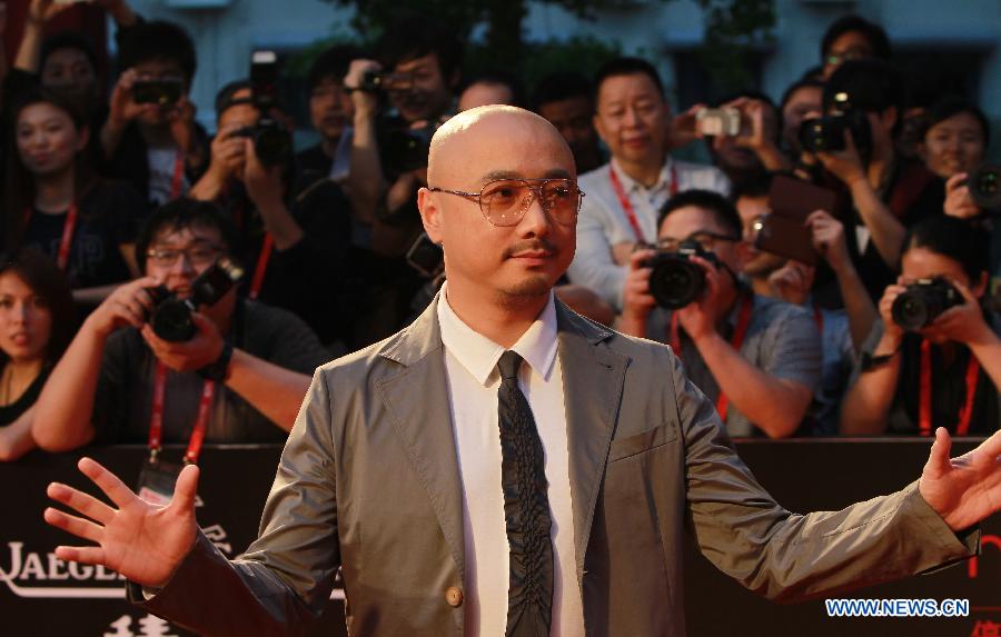 Director and actor Xu Zheng greets audience while arriving on the red carpet for the opening ceremony of the 16th Shanghai International Film Festival in Shanghai, east China, June 15, 2013. (Xinhua/Pei Xin)