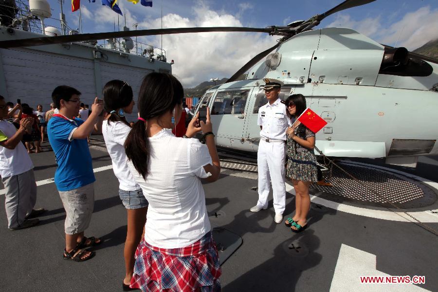 A soldier poses for photos with a visitor on the missile destroyer "Harbin" of the 14th Escort Taskforce of the Chinese Navy on Victoria Harbour, Seychelles, June 16, 2013. (Xinhua/Rao Rao)