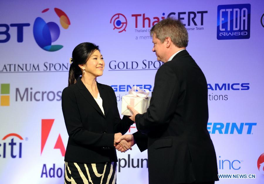 Thai Prime Minister Yingluck Shinawatra (L) accepts a gift during the opening ceremony of the 25th annual Forum of Incident Response and Security Teams (FIRST) conference in Bangkok, capital of Thailand, June 17, 2013. Under the theme of "Incident Response: Sharing to win", the five-day conference brings together leading experts from all over the world to share ideas on international security. (Xinhua/Gao Jianjun)
