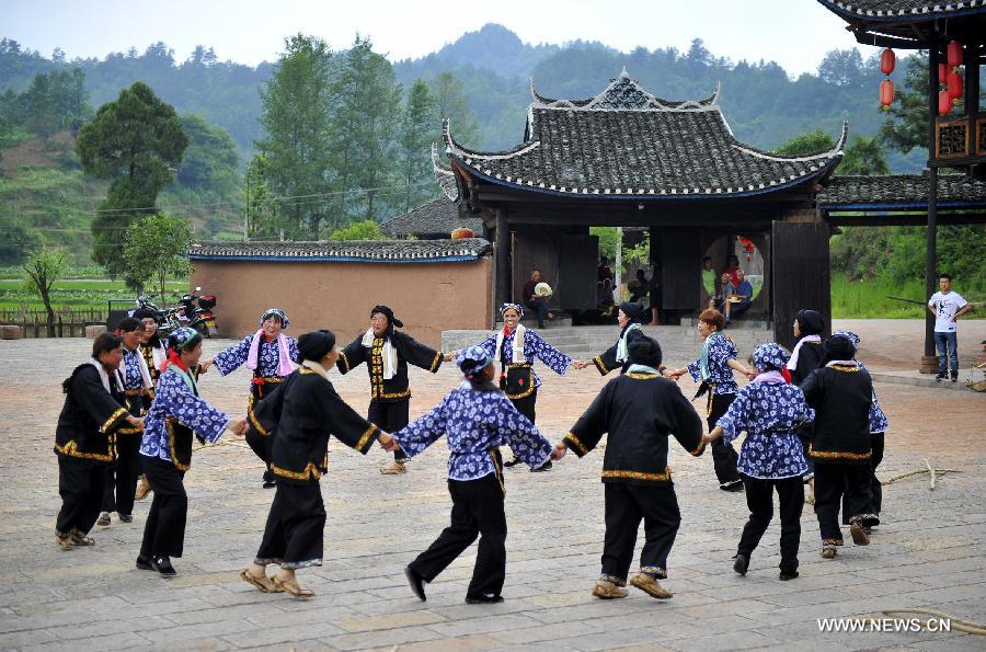 Villagers dance in front of a wooden Diaojiaolou, or stilted house in Shiyanping Village, Wangjiaping Township of Zhangjiajie City in central China's Hunan Province, June 16, 2013. The Shiyanping Village, located in the southeast of Wangjiaping, is one of the regions in Hunan where stilted houses are well preserved. With a toal of 182 existing stilted houses of the Tujia ethnic group, the village was listed as the seventh batch of important heritage sites under state protection in 2013. (Xinhua/Shao Ying)