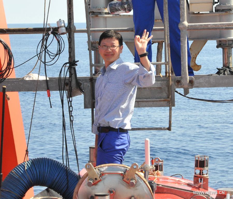 Qiu Jianwen, a scholar of ocean bio-diversity and fishing resource protection with Hong Kong Baptist University, salutes to the crew members before entering China's manned deep-sea submersible Jiaolong aboard its support ship Xiangyanghong 09 in the South China Sea, June 19, 2013. The Jiaolong manned deep-sea submersible on Wednesday carried its second scientist Qiu Jianwen as a crew member during a deep-sea dive. Jiaolong left east China's city of Jiangyin on June 10 for its first voyage of experimental application. The 113-day mission will include experiments on Jiaolong's positioning system, as well as deep-sea ecological and geological surveys in the South China Sea, biological surveying and geological sampling in the Pacific Ocean. (Xinhua/Zhang Xudong)