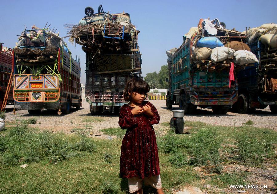 An Afghan refugee girl stands in front of loaded trucks near the United Nations High Commissioner for Refugees (UNHCR) registration center before returning to Afghanistan in northwest Pakistan's Peshawar, on June 20, 2013. Some 45.2 million people worldwide are under forced displacement due to persecution, conflict, generalized violence and human rights violations by the end of 2012, said an annual report released by the United Nations High Commissioner for Refugees (UNHCR) Wednesday. Developing countries hosted over 80 percent of the world's refugees, compared to 70 percent a decade ago, as the report noted, with Pakistan as the country hosting the largest number of refugees worldwide. (Xinhua/Ahmad Sidique)