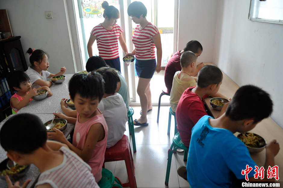 Volunteers help the 11 children with their lunch at noon. It has been 5 years since Li established the non-profit classroom specifically for children with autism in Taiyuan, north China’s Shanxi province. (Photo by Weiliang/ Chinanews.com)