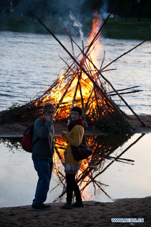 People stand by a bonfire to celebrate summer solstice in Lapland, north Finland in the Arctic Circle, in June 21, 2013. As Lapland situates in the Arctic Circle, there happens polar day in Summer solstice. Night and day the midnight sun stays above the horizon.(Xinhua/Yan Ting) 