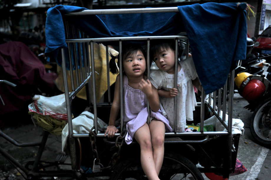 Two little girls were locked in a cage-like tricycle on the roadside of Binjiang Xilu in S China’s Guangxi on June 18, 2013. (Photo/ youth.cn)