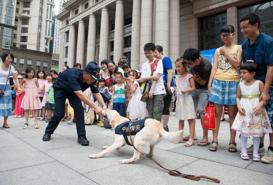 Visitors watch a detection dog performing during an "open day" of the Customs in Guangzhou, capital of south China's Guangdong Province, June 23, 2013. An "open day" activity was held here for the residents to know about the works of drug-sniffing dogs. (Xinhua/Mao Siqian) 