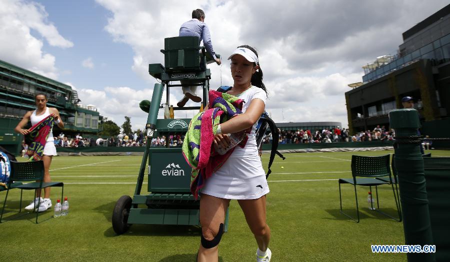 Zheng Jie (R) of China leaves the court after the first round of ladies' singles against Caroline Garcia of France on day 2 of the Wimbledon Lawn Tennis Championships at the All England Lawn Tennis and Croquet Club in London, Britain on June 25, 2013. Zheng lost 0-2. (Xinhua/Wang Lili)