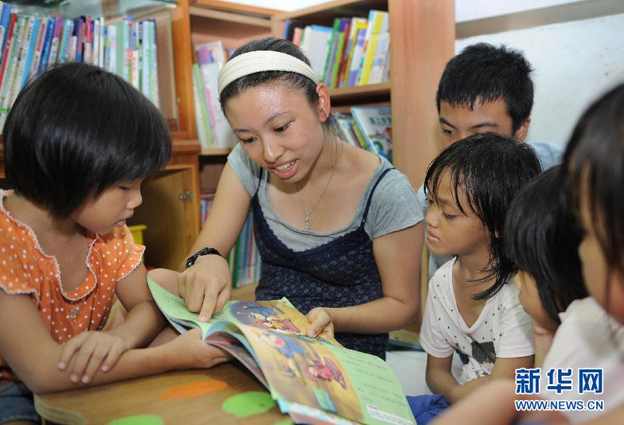 Teacher Huang Yanyu (second from left) helps the children with their study on June 20, 2013. (Photo/Xinhua)