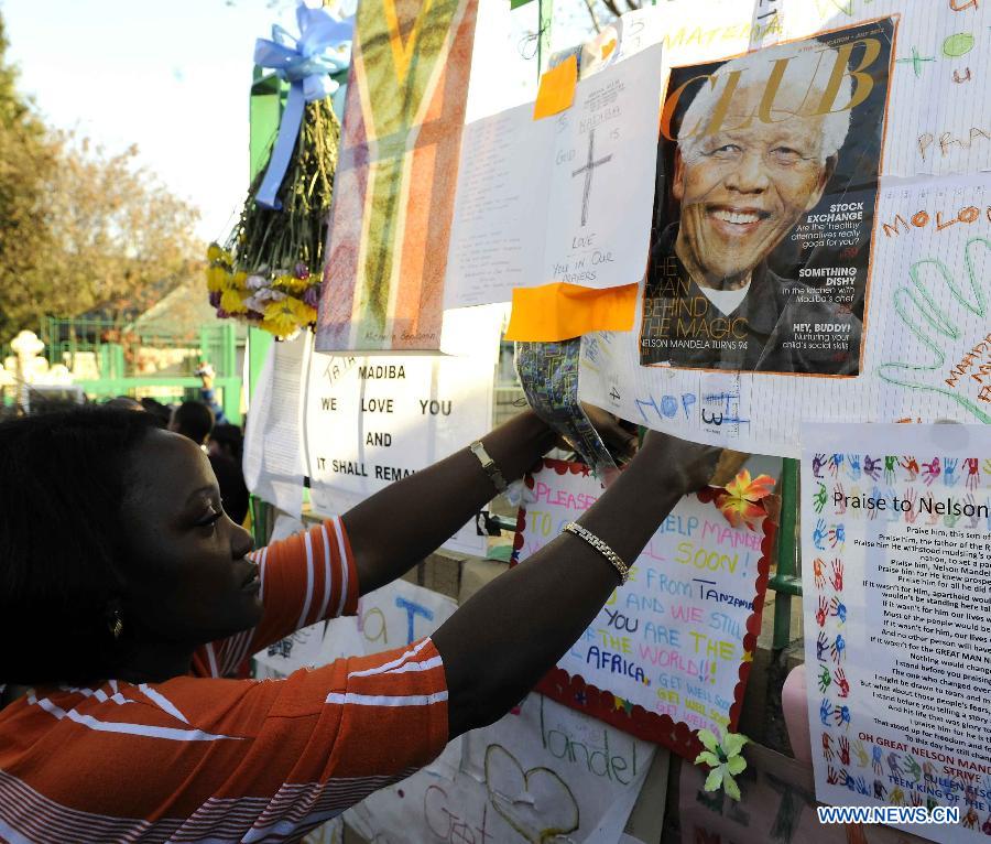 A local resident pastes a card on a wishing board outside the hospital where South Africa's anti-apartheid icon Nelson Mandela is treated in Pretoria, South Africa, to pray for Mandela, June 26, 2013. South Africa's President Zuma said on Wednesday that Mandela's condition "remains in a critical condition in hospital we must keep him and the family in our thoughts and prayers every minute." (Xinhua/Li Qihua) 