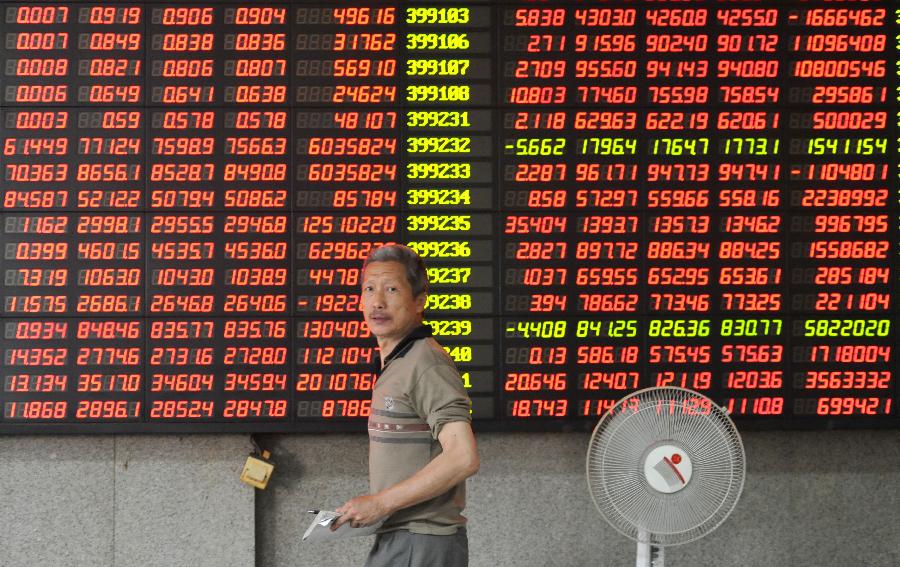 An investor walks past the screen showing stock information at a trading hall of a securities firm in Nanjing, capital of east China's Jiangsu Province, June 27, 2013. Chinese shares lost a mild rebound in early morning trade and ended in negative territory on Thursday. The benchmark Shanghai Composite Index shed 0.08 percent, or 1.48 points, to end at 1,950.01. The Shenzhen Component Index shrank 0.30 percent, or 22.07 points, to 7,544.33. (Xinhua)