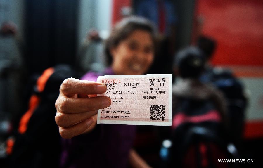 A passenger for K1124 train from northeast China's Harbin to south China's Haikou shows her ticket in Harbin, capital of northeast China's Heilongjiang Province, June 28, 2013. The train which travels 4,458 kilometers for 65 hours has connected China's northernmost capital city Harbin of Heilongjiang Province with southernmost capital city Haikou of Hainan Province. (Xinhua/Wang Kai) 